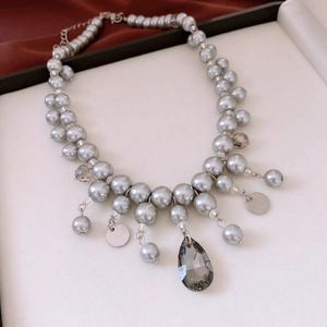 Dettaglio della collana di perle di vetro grigio con pendente in cristallo a goccia