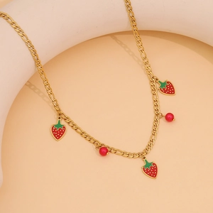Collier mignon en acier doré avec pendentifs fraises rouges et perles sur fond neutre