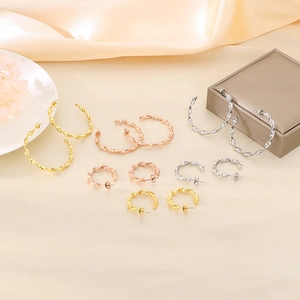 Selection of twisted hoop earrings in gold, silver and rose gold on elegant silk cloth