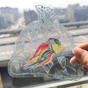 Hand holding a rainbow suncatcher window sticker featuring a colorful jellyfish design