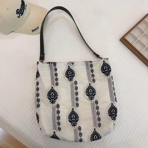 Detailed close-up of ethnic embroidery on white linen tote bag with leather straps