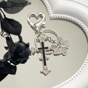 Gothic silver cross and butterfly keychain with heart carabiner on a mirror surface