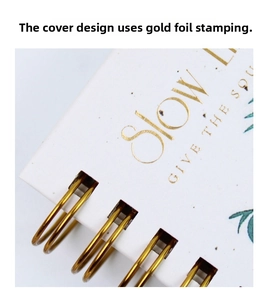 Macro detail of A6 spiral notebook featuring gold foil stamped lettering and wire binding