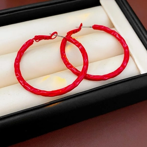 Close-up of red textured hoop earrings with silver pins displayed in a jewelry box