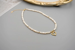 Detail of freshwater pearl necklace with gold hollow heart pendant and lobster clasp