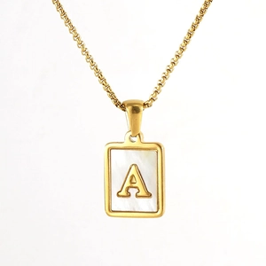 Detail of square gold pendant necklace with white mother of pearl and letter A engraving
