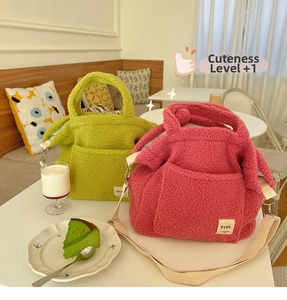 Detail of plush faux shearling tote bags in green and pink with adjustable shoulder straps