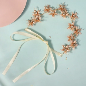 Detail of rose gold flower headband with rhinestones and beads on beige ribbons