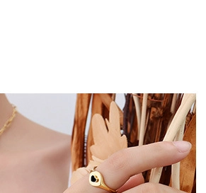 Close-up of a minimalist gold heart ring with black enamel finish on a model's finger