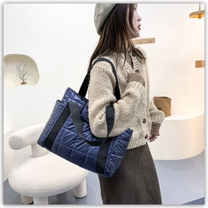 Detail of dark blue quilted tote bag showing square stitching and puffer texture