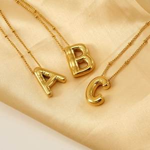 Golden balloon style initial pendant necklace with puffed letter A B C on champagne satin