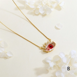 Macro shot of gold-plated evil eye necklace with red pupil and clear zircon eyelashes