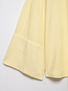 Detail view of the yellow linen blend fabric showing fine stitching and texture