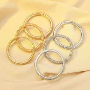 Macro detail of gold and silver spring coil bracelets on premium silk background