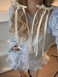 Close-up of cream white ribbons used as hair bows on wavy blonde hair with lace dress detail