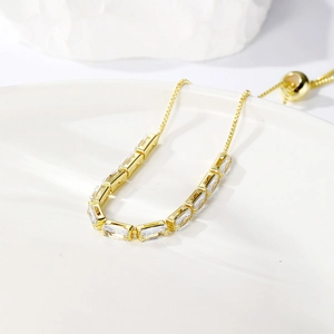 Detail of adjustable gold bracelet featuring baguette-cut zircon crystals and slider clasp