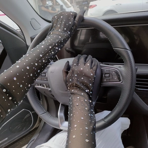 Close-up of black mesh lace gloves with rhinestones worn while driving a car