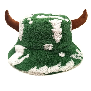 Detail of plush green cow print bucket hat with 3D brown horns for winter warmth