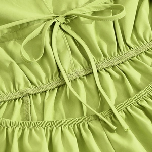 Detail of lime green dress showing drawstrings and elastic pleated texture on fabric