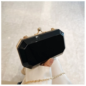 Close-up of black octagonal acrylic clutch bag with gold metal frame and clasp