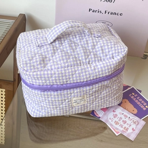 Detailed view of a purple gingham quilted cosmetic bag in a lifestyle setting