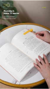 Macro shot of a yellow silicone automatic bookmark following page turns on an open book