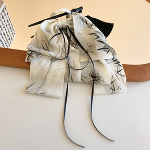 Detail of silk hair ribbon with bamboo ink pattern and black tassel on a wooden frame