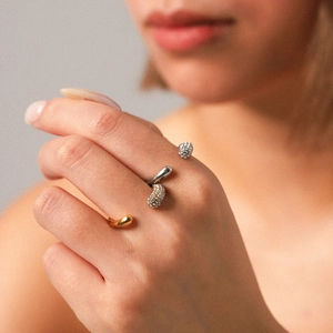 Close-up of stacked gold smooth spiral ring and silver pavé zircon wrap ring on finger