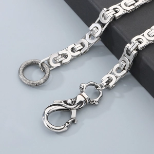 Macro shot of silver punk cuban chain featuring a skull buckle and snake textured ring