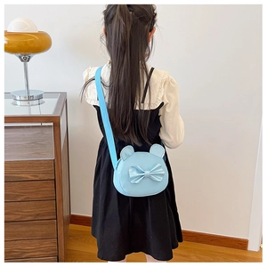 Rear view of a child wearing a light blue round cartoon bag with a shiny bow detail
