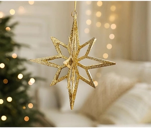 Close-up of a sparkling gold glitter star ornament hanging on a festive Christmas tree