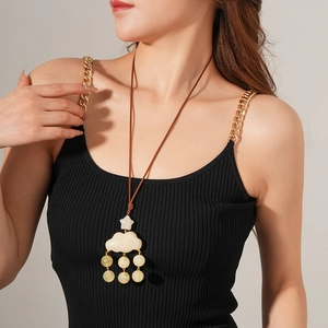 Close-up of a white cloud and star pendant with yellow beads on a brown cord necklace