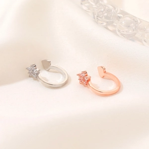 Detailed close-up of heart-shaped ear clips in silver and rose gold with pavé crystals