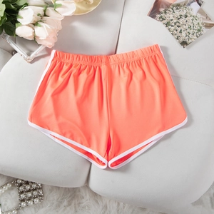 Flat lay of vibrant orange sports shorts with white trim and elastic waistband texture