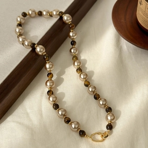18K gold plated tiger eye and pearl necklace with retro metal clasp on white fabric