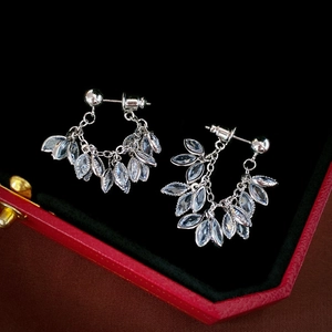 Macro detail of silver leaf earrings with zircon crystals in a premium jewelry gift box