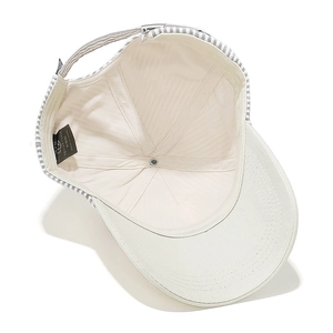 Detail of cream canvas baseball cap showing interior stitching and striped strap closure