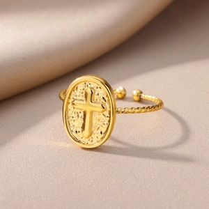 Macro view of 18k gold plated stainless steel ring with embossed cross on hammered oval face