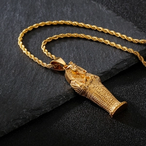 Detailed view of an 18K gold Pharaoh pendant on a grey stone slab with rope chain