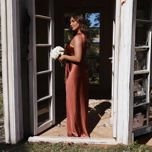 Gros plan d'une robe longue en satin rouille montrant le dos nu et le tissu soyeux