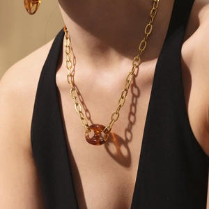 Gouden grove ketting met ovale barnsteenkleurige hanger gedragen door een model