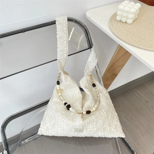 Détail du sac jacquard blanc avec chaîne perlée et texture florale sur une chaise