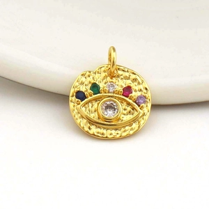 Detail of 18k gold heart pendant with hammered texture and colorful evil eye gemstones