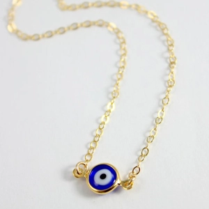 Bohemian gold chain necklace featuring a blue evil eye pendant on a white background