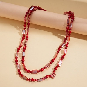 Détail d'un collier bohème double épaisseur avec perles rouges et pendentifs coquillage