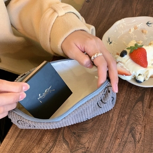 Detail of grey corduroy makeup bag with cartoon embroidery in a lifestyle setting