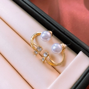 Macro shot of gold-plated C-shaped earrings with round white pearls and sparkling crystals