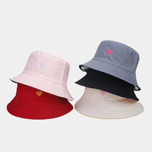 Détail de cœur brodé sur cinq bobs réversibles en coton coloré pour la protection solaire