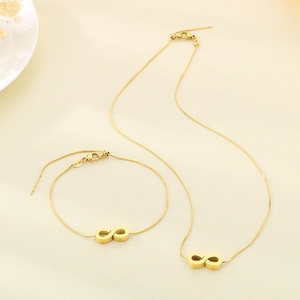 Detailed top view of gold infinity symbol necklace and bracelet set on beige fabric