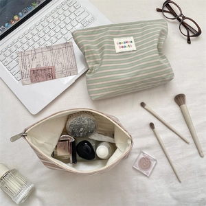 Lifestyle shot of large capacity striped canvas makeup bags on a desk with accessories